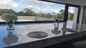 a glass table with two vases with flowers on it at Bella Casa Total House in São Francisco +5 photos