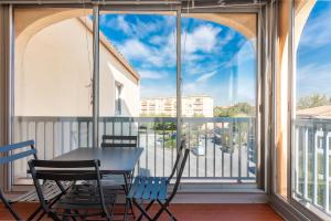a balcony with a table and chairs and a window at Appartement cocooning in Fréjus