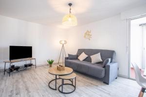 a living room with a couch and a table at Appartement cocooning in Fréjus