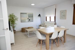 a dining room with a table and white chairs at Apartamentos Lua in O Grove
