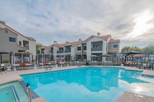 einen Pool in einem Resort mit Stühlen und Sonnenschirmen in der Unterkunft Lush Golf Pickleball Pool Hot Tub King Bed Parking in Scottsdale