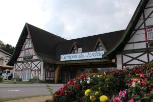 a building with a sign on it with flowers at Pousada Serrano in Campos do Jordão