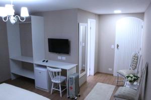a living room with a desk with a tv and chairs at Pousada Serrano in Campos do Jordão