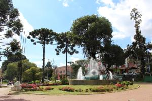 a fountain in a park with flowers and trees at Pousada Serrano in Campos do Jordão