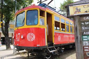 a red and yellow trolley car on a street at Pousada Serrano in Campos do Jordão