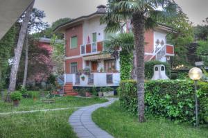 a house with a palm tree and a sidewalk at Residence Villa Laura in Lignano Sabbiadoro