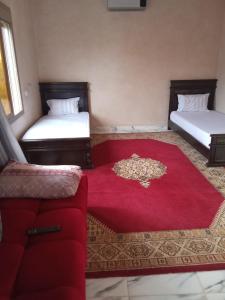 a room with two beds and a red carpet at Villa tagmouti in Aghmat