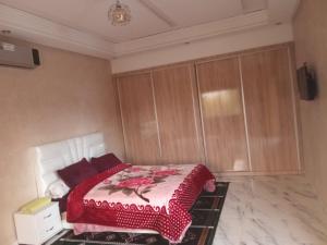 a bedroom with a bed with a red blanket on it at Villa tagmouti in Aghmat