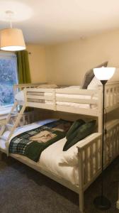 a bedroom with two bunk beds and a lamp at Y Fedw Wen in Bont Newydd