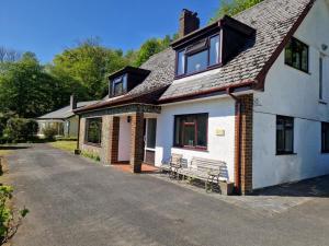 a white house with a bench in the driveway at Y Fedw Wen in Bont Newydd