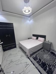 a white bedroom with a bed and a rug at SKA Zac Mbao in Rufisque