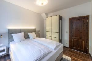 a bedroom with a large white bed and a wooden door at Ferienwohnung "Kleines Meer" in Waren