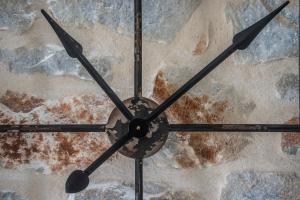 a large clock hanging from a stone wall at The Olive Yard in Gythio