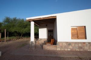 a white house with a porch and a pillar at Cabañas y dormis Zgris in Tinogasta