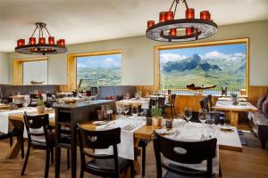 a restaurant with tables and chairs with mountains in the background at Frutt Mountain Resort in Frutt