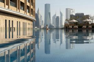 a woman sitting in a pool with a city in the background at Kempinski Central Avenue Dubai in Dubai