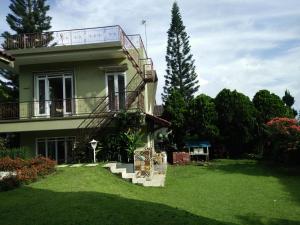 a house with a balcony and a grass yard at Villa Bougenvile Lembang Asri in Lembang