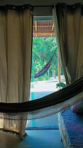 a hammock in a room with a window at Pousada riacho santa cruz in Barreirinhas