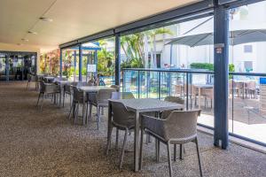 a restaurant with tables and chairs and windows at Mantra Marina Hotel Room in Urangan