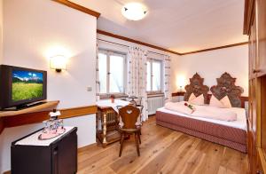 ein Hotelzimmer mit 2 Betten und einem TV in der Unterkunft Alpenrose in Mittenwald