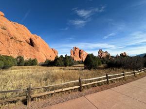 a wooden fence in a field with red rocks at Timber Lodge #11 in Colorado Springs