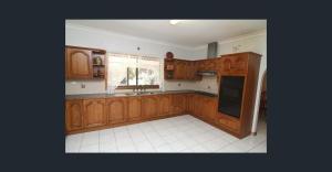 a kitchen with wooden cabinets and a black refrigerator at Farm house in Monash +10 photos