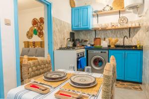 une cuisine avec des armoires bleues et une table avec des assiettes dans l'établissement L'authentique place, à Essaouira 10 autres photos