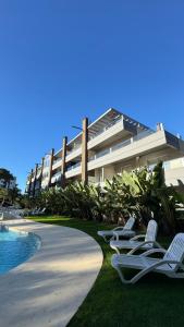 a row of lawn chairs next to a building at Departamento 3 ambientes - Amarras Pinamar in Pinamar