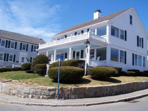 a white house with bushes in front of it at Beach & King Street Inn in Rockport