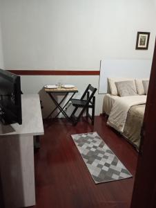 uma sala de estar com uma cama, uma mesa e uma televisão em House Campos 2 em Campos de Jordão