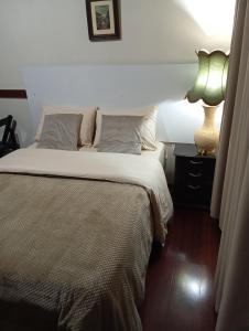 um quarto com uma cama e um abajur em uma mesa de cabeceira em House Campos 2 em Campos de Jordão