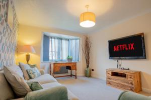 a living room with a couch and a tv at Stylish 3-Bed, Garden & Secure Parking - M5 5 mins in Hindlip