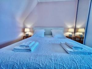 Un dormitorio con una cama azul con toallas. en MA ZI BIHAN Family home, en Carantec