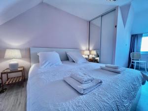 Un dormitorio blanco con una cama con toallas. en MA ZI BIHAN Family home, en Carantec