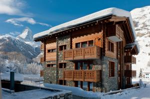 une cabane en rondins dans la neige avec des montagnes en arrière-plan dans l'établissement Mountain Paradise, à Zermatt