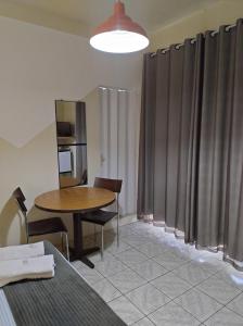 a room with a table and chairs and curtains at Pousada Flay 7 minutos do Aeroporto de Florianópolis in Florianópolis