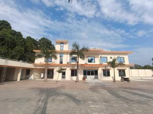 un grand bâtiment avec des palmiers devant dans l'établissement Hotel O Home Kanak Hotel & Resort Homestay, à Ayodhya