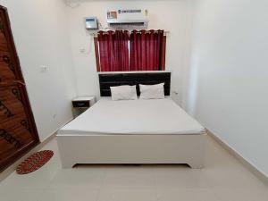 - un lit blanc dans une chambre avec rideau rouge dans l'établissement Hotel O Home Kanak Hotel & Resort Homestay, à Ayodhya 26 autres photos