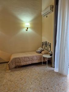 Cama en habitación con lámpara y mesa en GLI APPARTAMENTI DI PALAZZO UMBERTO I, en Catania