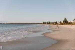 a person walking on a beach next to the ocean at Serene Getaway in Callala Beach