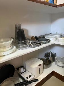 ein Küchenregal mit Tellern und Geschirr und einem Toaster in der Unterkunft Home 24 Transient in Sampong