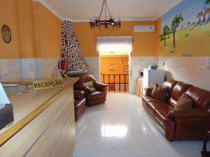 a living room with leather couches and a kitchen at Residencial as Canárias in Ponte de Sor