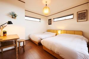 Dos camas en un dormitorio con escritorio y dos ventanas. en Maigre atelier, en Ito