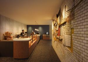 a restaurant with a counter and a person in a kitchen at OMO7 Yokohama by Hoshino Resorts in Yokohama