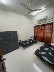 a room with two beds and cabinets in it at Epy Homestay Teluk Intan in Teluk Intan