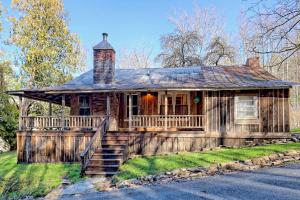 an old wooden house with a chimney on top at Historic Cabin with Porch and Firepit 5 Minutes from Bryson City in Bryson City