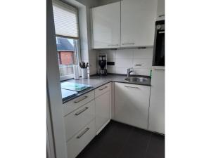a kitchen with white cabinets and a sink and a window at Liefke in Haus Seehund in Wittdün