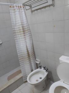 Un baño con inodoro y cortina de ducha. en SaJulAgos963, en La Porteña