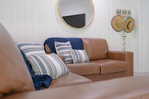 a living room with a brown couch and a mirror at Liana One Coastal Mission Vibe two bedroom apartment in Mission Beach