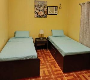 ein Zimmer mit zwei Betten und einem Tisch mit Lampe in der Unterkunft Garden INN in Santander